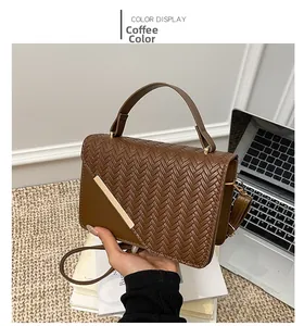 Close-up of brown woven faux leather crossbody bag with elegant gold metal bar detail