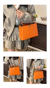 Détail du sac à main orange grainé avec logo en V et bandoulières amovibles