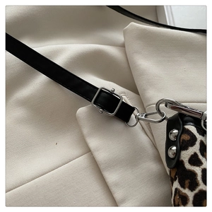 Detail of leopard print fabric with black leather strap and silver metal buckle adjustments