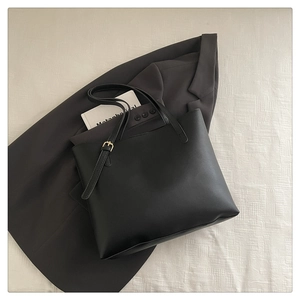 Detail of adjustable strap with gold buckle on a black minimalist leather tote bag