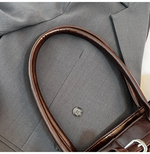 Detail of curved dark brown oily leather handle on a vintage minimalist tote bag