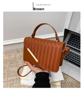 Detail shot of brown woven texture bag with gold metal trim and flap closure