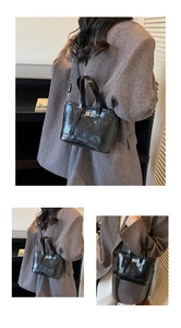 Detail of glossy black tote bag with silver metal twist lock and detachable strap