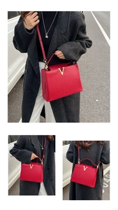 Détail d'un sac à main rouge en cuir grainé avec un logo en V doré élégant et sophistiqué