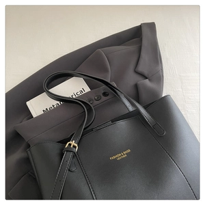 Detailed view of black leather tote bag with gold lettering and metal buckle accents