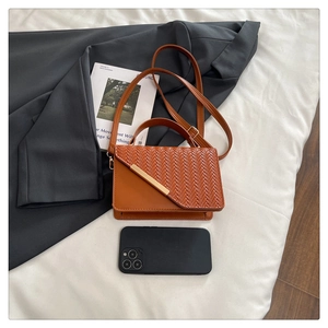 Mini-Handtasche aus braunem Webkunstleder mit Goldverschluss im Größenvergleich zum Smartphone
