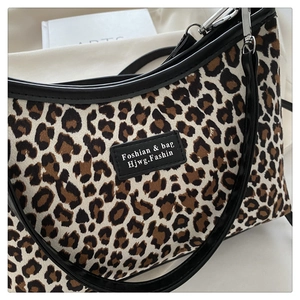 Close-up of leopard print shoulder bag featuring a black logo patch and thin strap