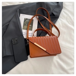 Detailed view of caramel brown woven leather crossbody bag with gold metal trim and strap