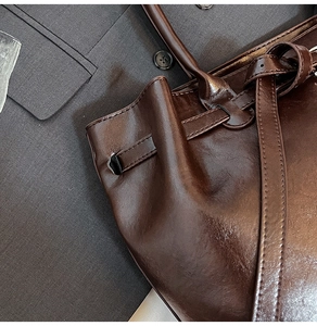 Detail of glossy brown leather tote bag with vintage texture and adjustable strap