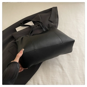 Macro view of a black tote bag showing smooth matte texture and sleek side seams