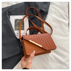 Close-up of brown crossbody bag with woven texture, gold bar and handle detail