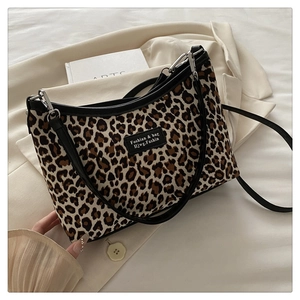 Detail shot of leopard print tote bag featuring black leather trim and metal hardware
