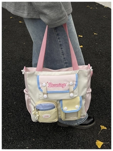 Outdoor shot of a multi-pocket macaron nylon tote bag worn on a model's shoulder