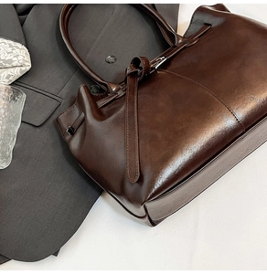 Detail of deep brown glossy leather tote bag with elegant ties and slim handles