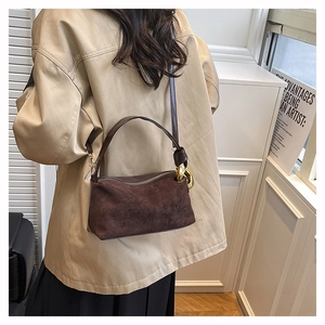 Detail of a dark brown suede shoulder bag with elegant gold chain metal buckle