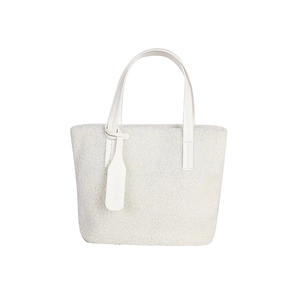 Minimalist cream white plush bucket bag with leather handles and decorative tag