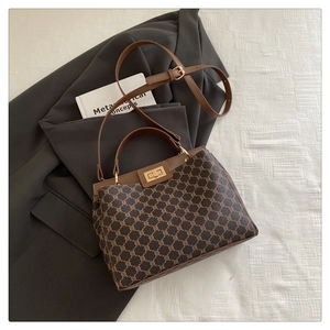 Détail du sac seau vintage avec toile monogramme, bordure en cuir marun et fermoir doré
