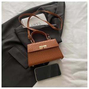 Détail d'un sac à main marron tissé avec fermoir doré et bandoulière amovible