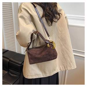 Close-up of the dark brown matte suede texture and gold metal chain buckle detail on bag