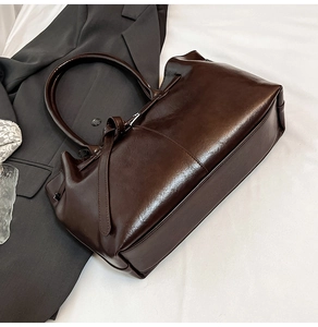 Detail of glossy dark brown leather tote bag with elegant decorative belt knot