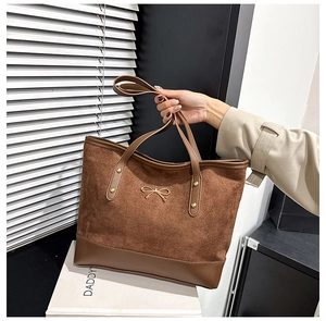 Close-up of brown suede tote bag with gold bow buckle and leather patchwork detail