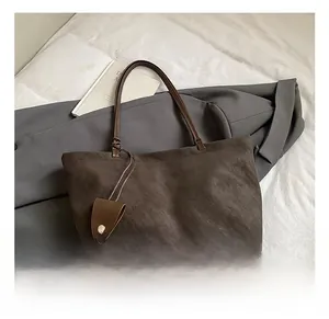 Detail of dark brown suede tote bag with slim leather handles and matching coin purse