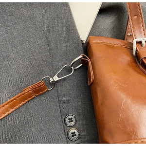 Detail of brown leather bag showing silver metal buckles and detachable strap