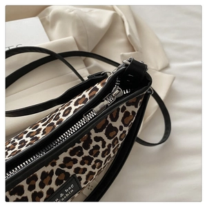 Detail of leopard print fabric texture and black leather strap with silver metal zipper