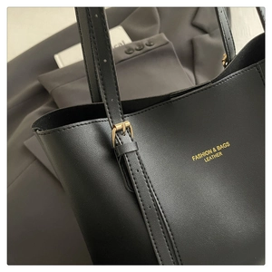 Detail of black pebbled leather tote bag with gold lettering and adjustable shoulder strap