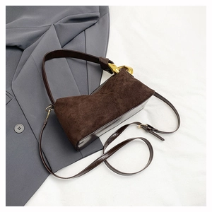 Detail of contrasting textures on dark brown handbag with gold hardware and suede panels