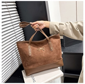 Detail of suede tote bag featuring a golden bow metal buckle and sturdy handles