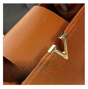 Détail de cuir grainé caramel avec une boucle métallique dorée en forme de V de luxe
