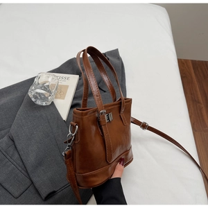 Detail of caramel quilted handbag with silver buckle over a classic grey blazer