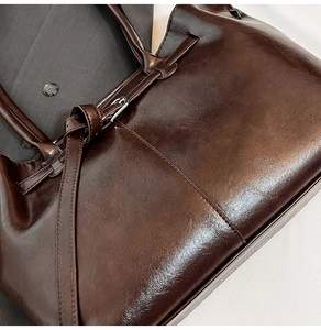 Close-up of dark brown glossy leather tote bag with metallic buckle and retro strap detail