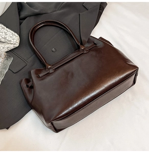 Detail of vintage dark brown tote bag with glossy finish and cylindrical dual handles