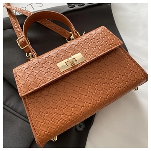 Détail d'un sac à main marron à texture tressée avec fermoir doré et bandoulière amovible