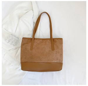 Detail of a large brown tote bag showing mixed textures of suede and smooth faux leather