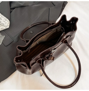 Deep brown matte tote bag featuring striped fabric lining and interior zip pocket detail