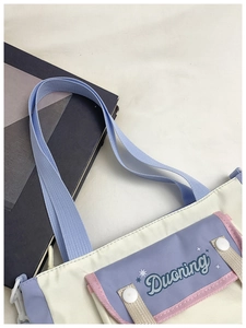 Close-up of contrast color canvas tote with purple flap pocket and Duoning star logo