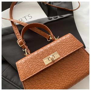 Détail du sac à main marron tressé avec un fermoir rotatif en métal doré élégant