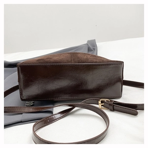 Detail of retro brown suede shoulder bag with polished leather trim and gold buckles
