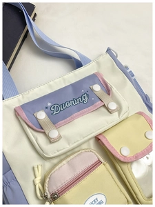 Detail of color-block canvas bag featuring functional pockets and contrast trim