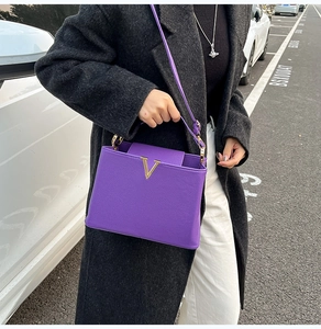 Détail du sac à main en cuir violet avec boucle métallique dorée en forme de V