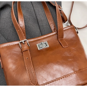 Detail of retro brown oil wax leather handbag featuring a polished silver metal twist lock