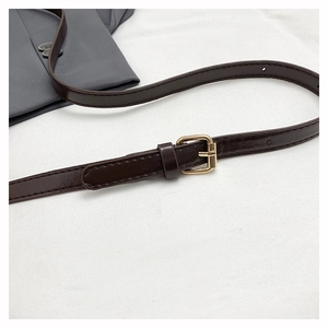 Close-up of adjustable dark brown faux leather shoulder strap with gold metal buckle