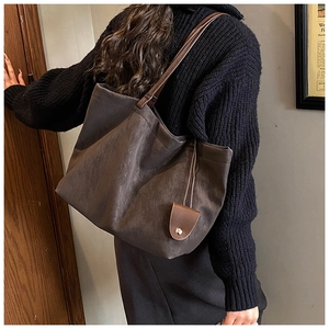 Macro view of dark brown suede tote bag with slim shoulder strap and leather pendant