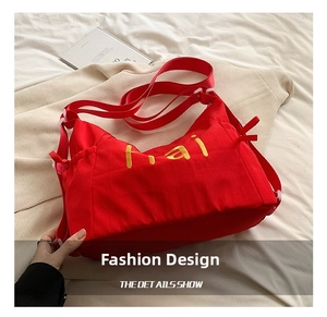 Macro detail of red canvas bag with yellow Hai embroidery and adjustable strap