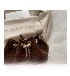Dettaglio della trama a scacchi intrecciata marrone scuro con catena dorata della borsa