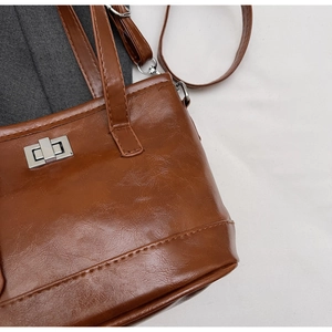 Detail of silver twist lock and pebble grain texture on brown leather handbag
