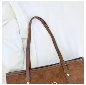 Detail of suede tote bag handle with golden metal rivets and premium texture